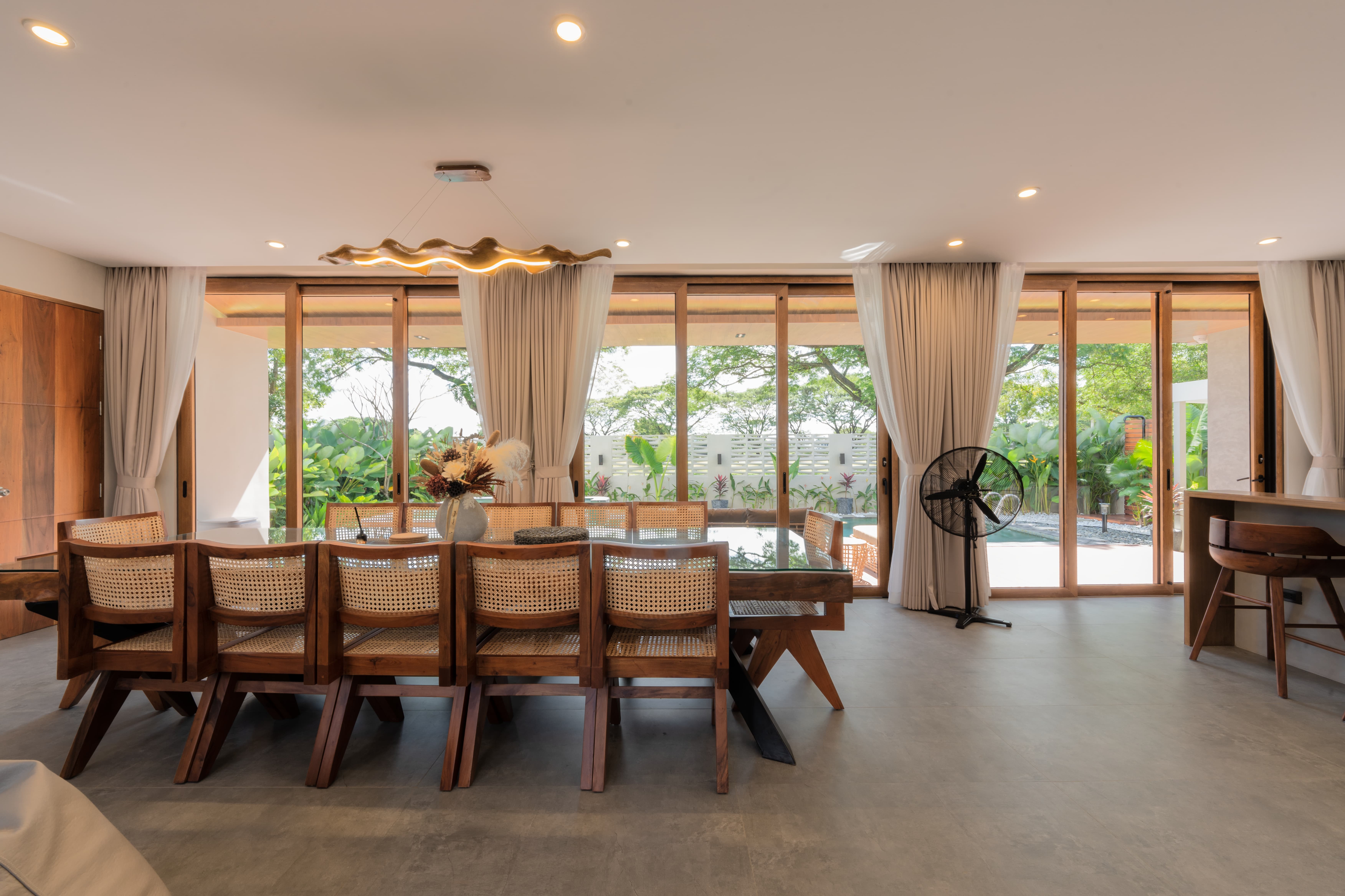 Long dining table with rattan chairs and garden view