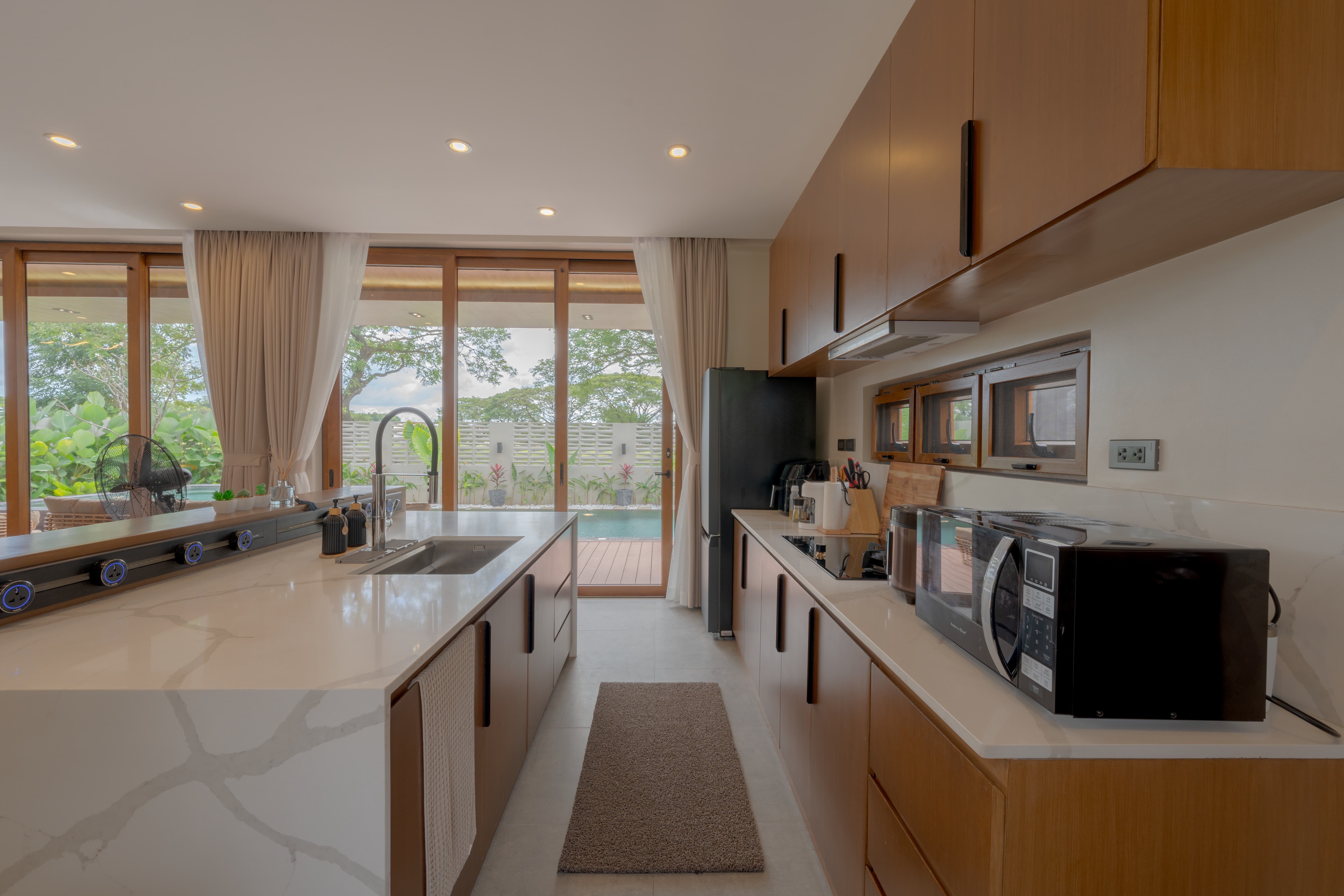 Full kitchen with marble counters opening to the pool