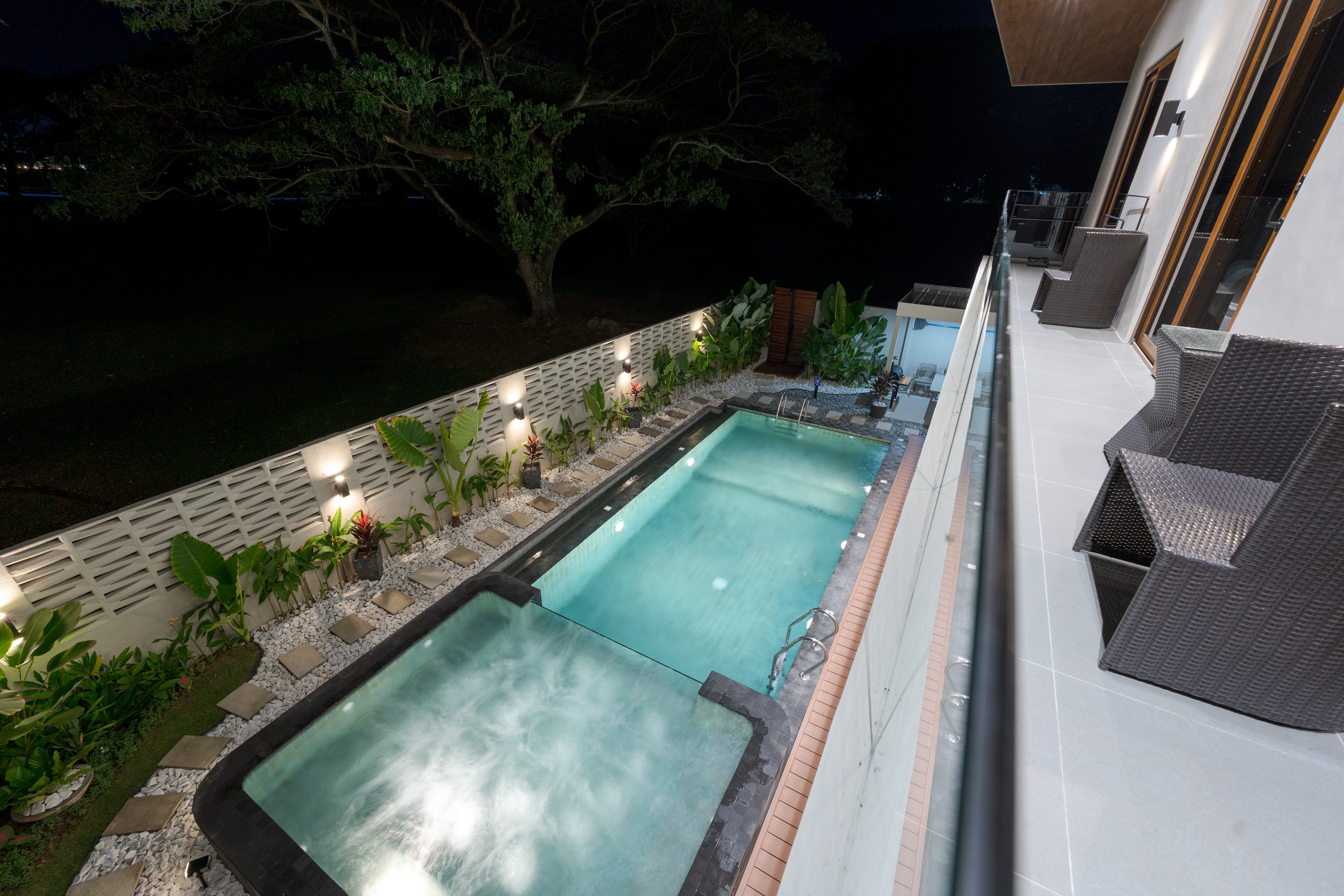 Pool and jacuzzi at night with deck lighting